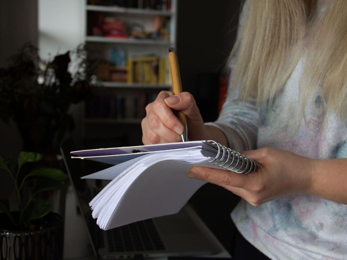 pen in hand writing in notebook