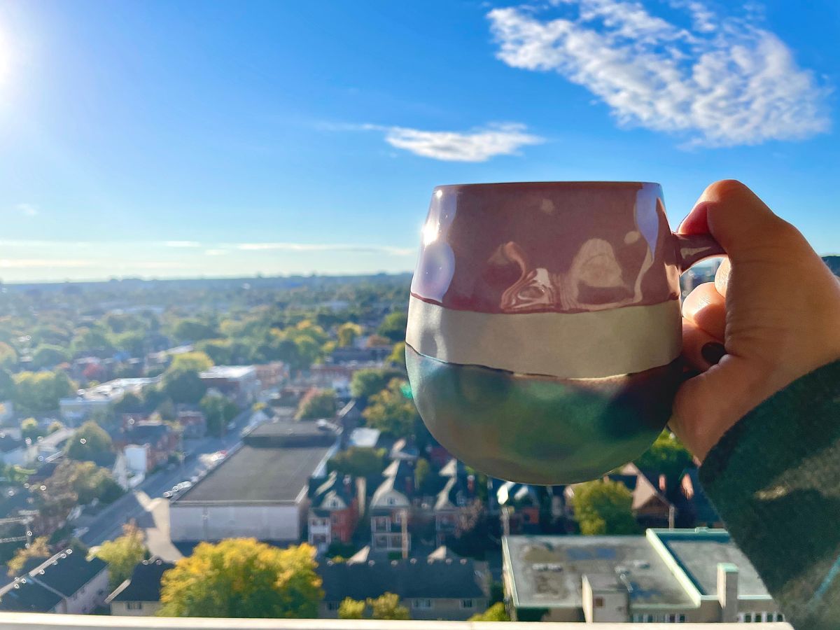 holding up a mug of coffee, a cheers to a beautiful blue sky and city views