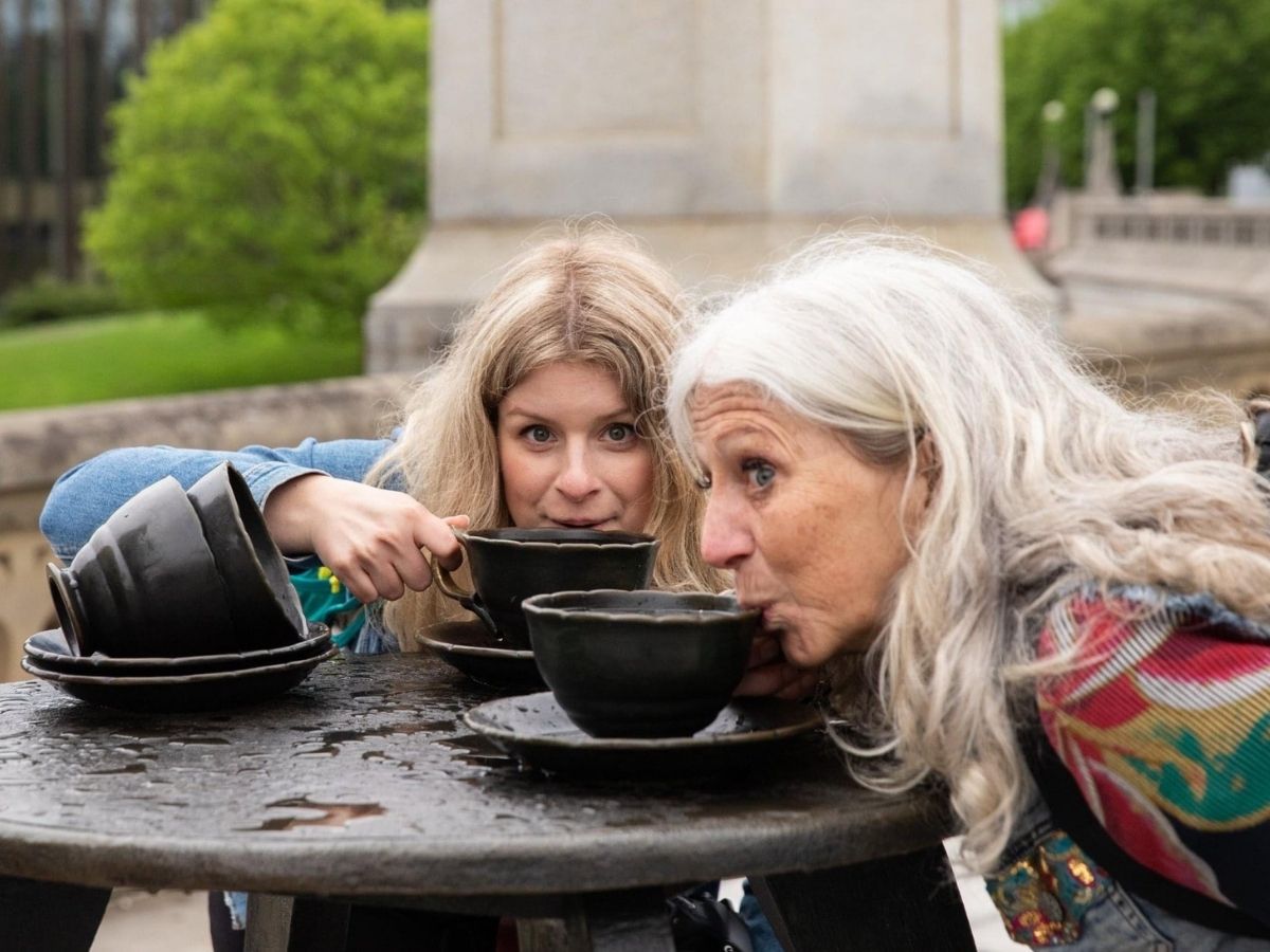 two women taking sips of tea from teacup statue - famous five