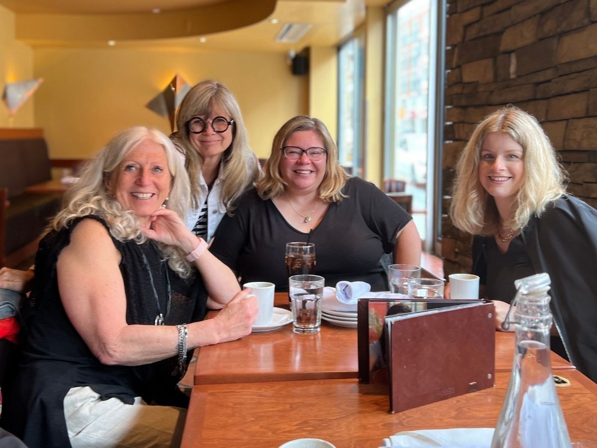 four women smile together for photo in restaurant
