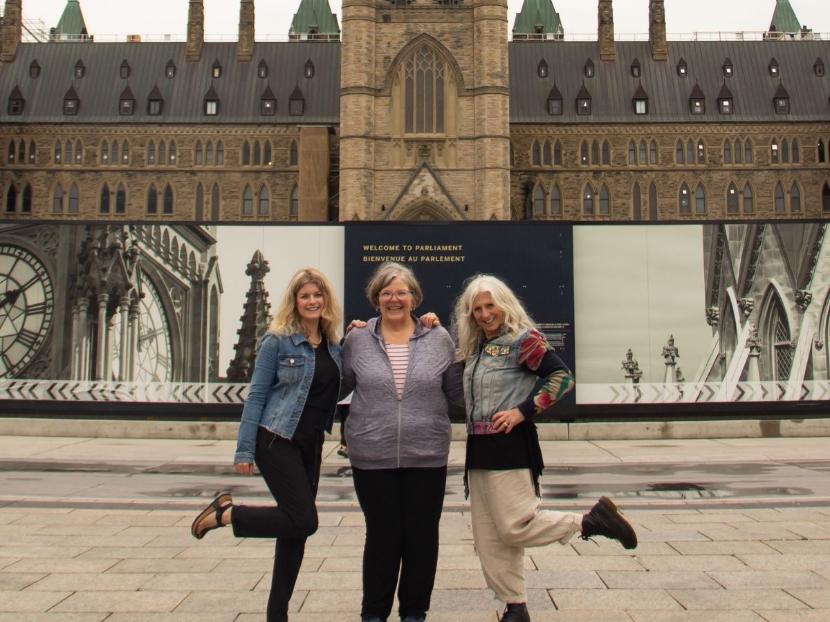 three women pose in front of Canadian Parliament Building